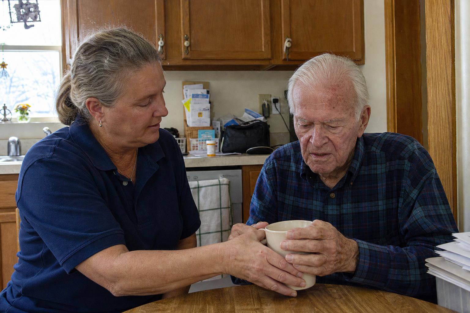 Caregiver and elderly man laughing over tea